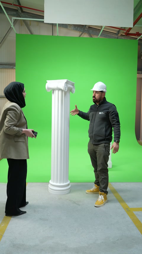Sunucu ve usta yeşil fon önündeki sütunu karşılıklı değerlendiriyor