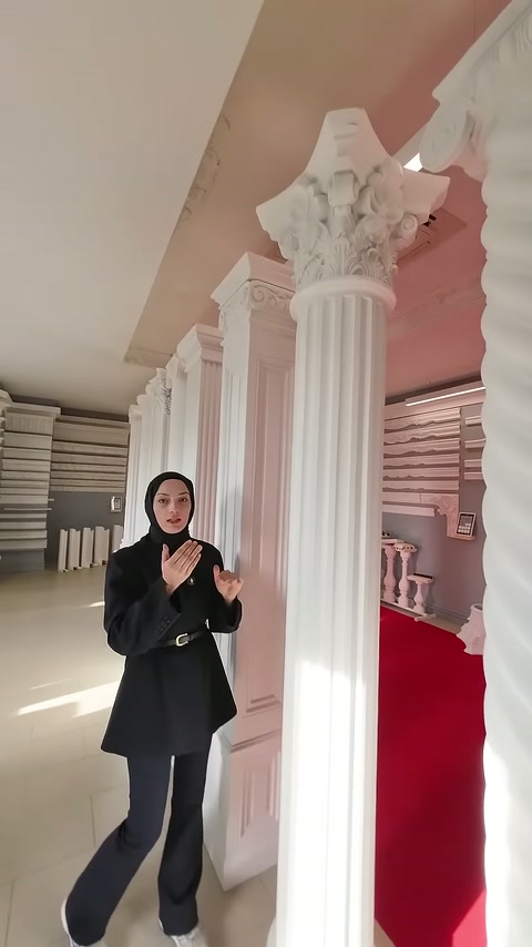 Sunucu, yüksek sütunun yivli yüzeyi önünde açıklama yapıyor.