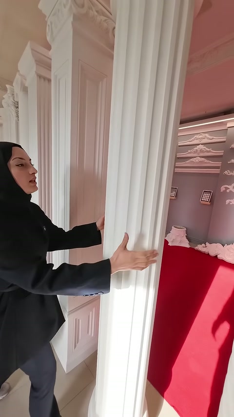 Sunucu, yivli sütunun yuvarlak gövdesini iki eliyle kavrıyor.