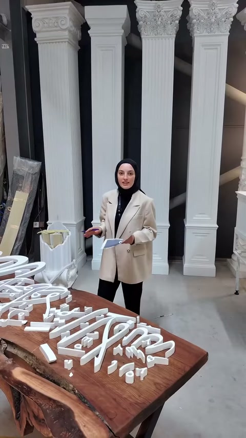 Sunucu, tamamlanmış poliüretan tabela elemanlarının yanında bilgi veriyor.