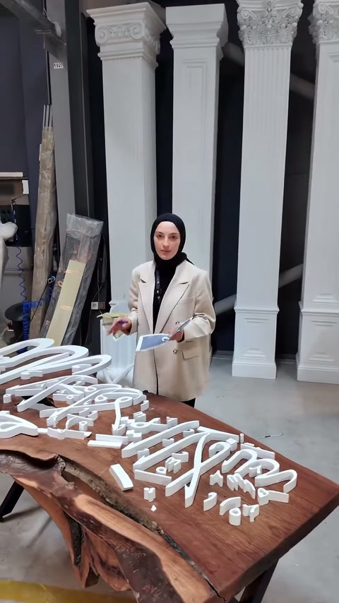 Sunucu, ahşap masadaki özel kesim harfleri eliyle işaretliyor.