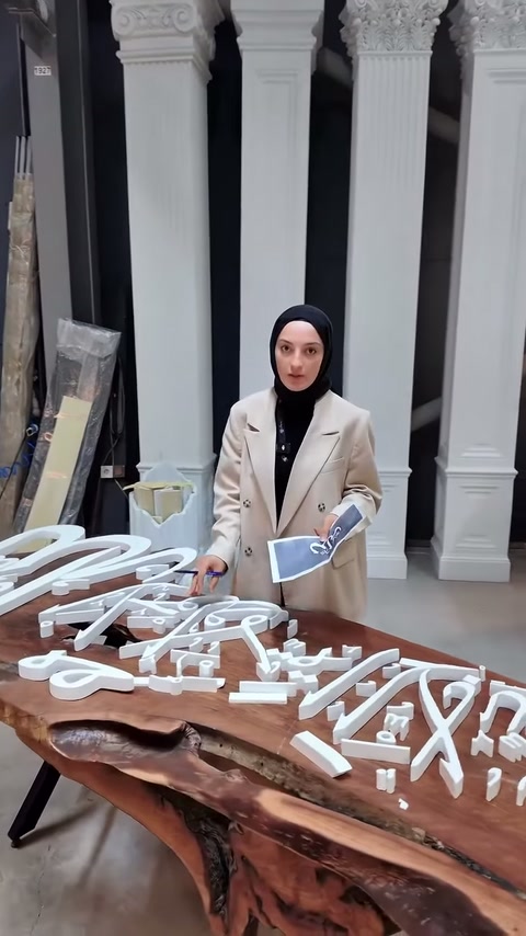 Sunucu, üretimi biten tabela parçalarını masanın yanında inceliyor.
