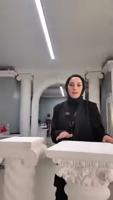Sunucu, geniş dikdörtgen tablayı eliyle işaret ederek anlatıyor.
