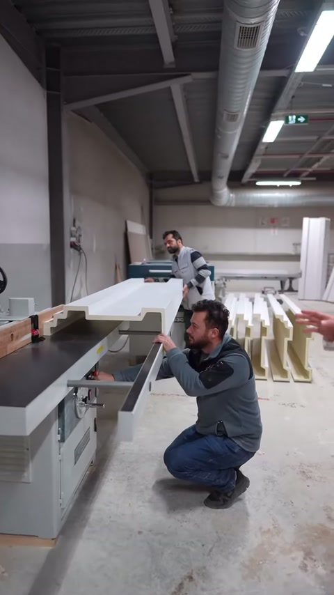 Usta çömelerek makine tablasındaki profilin kenar hizasını kontrol ediyor.