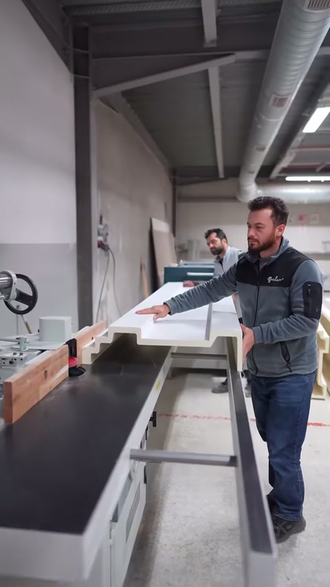 Usta, geniş profil parçasını kesim tablası boyunca dikkatlice ilerletiyor.