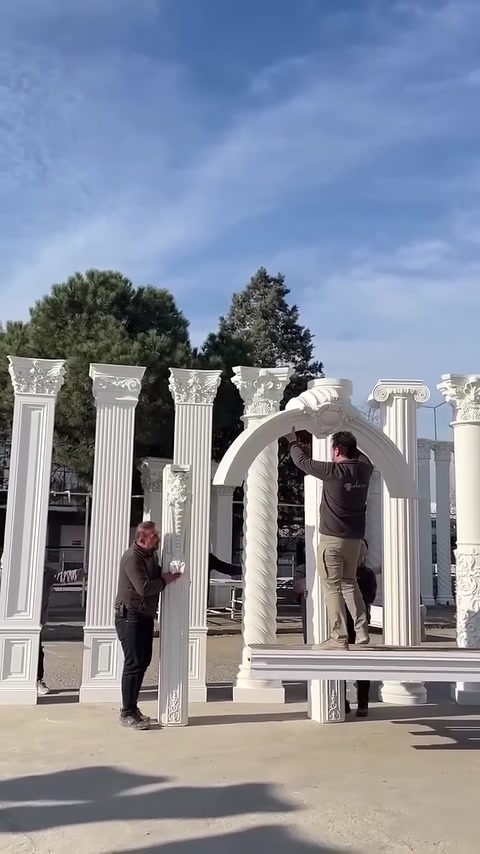 Çalışanlar kavisli dekoratif kemeri iki sütunun üzerine yerleştiriyor