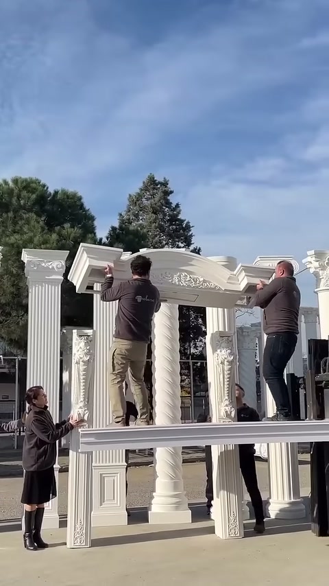 İki çalışan işlemeli üst parçayı sütun başlıkları boyunca dengeliyor