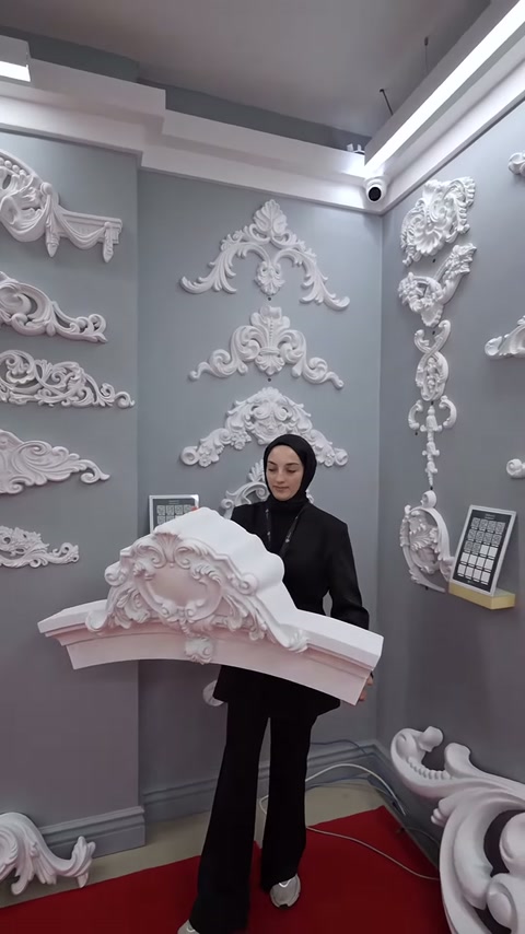 Sunucu büyük dekoratif alınlık parçasını iki eliyle önde tutuyor.