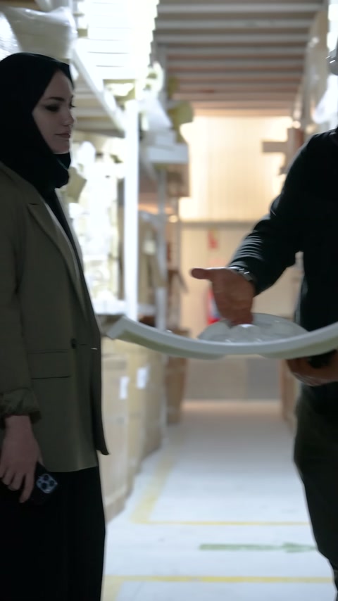 Kadın görevli eldeki kavisli süsleme parçasına yakından bakıyor