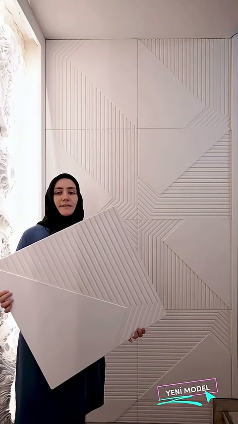 Sunucu, geometrik desenli paneli tamamlanmış iç duvar uygulaması önünde tutuyor.
