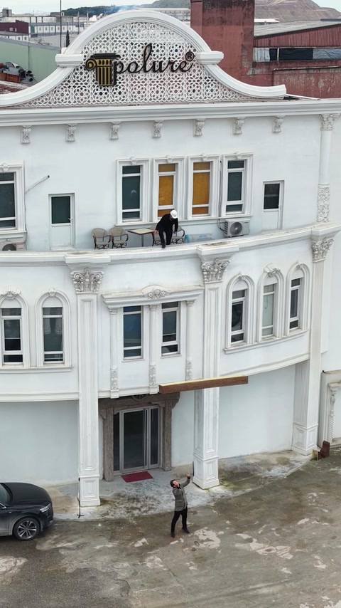 Uzun ahşap görünümlü kiriş beyaz yapının cephesinde yatay tutuluyor.