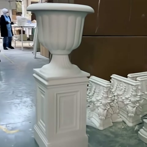 Beyaz dekoratif saksı, duvar panelleri bulunan atölyede tam boy görüntüleniyor.