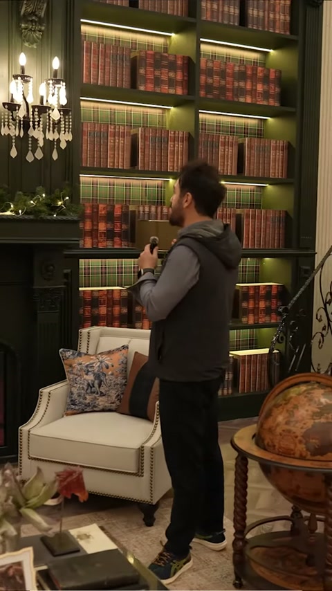 Koyu renk şömine cephesi, kitap rafları ve beyaz koltuklarla sergileniyor