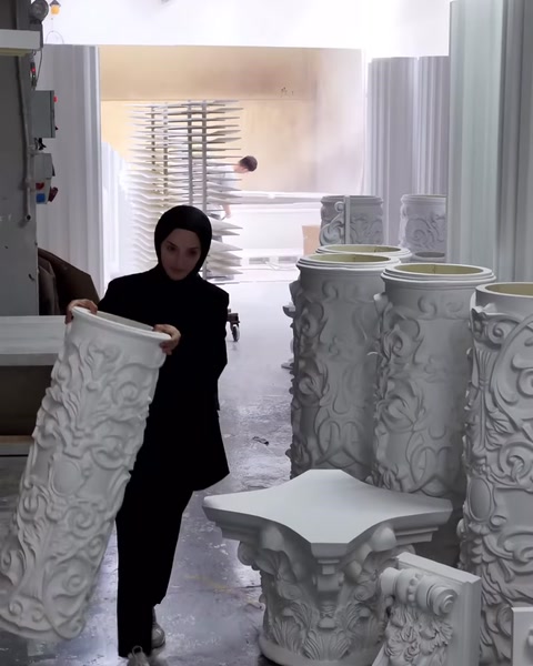 Çalışan, kabartmalı silindirik sütun parçasını üretim alanında inceliyor.