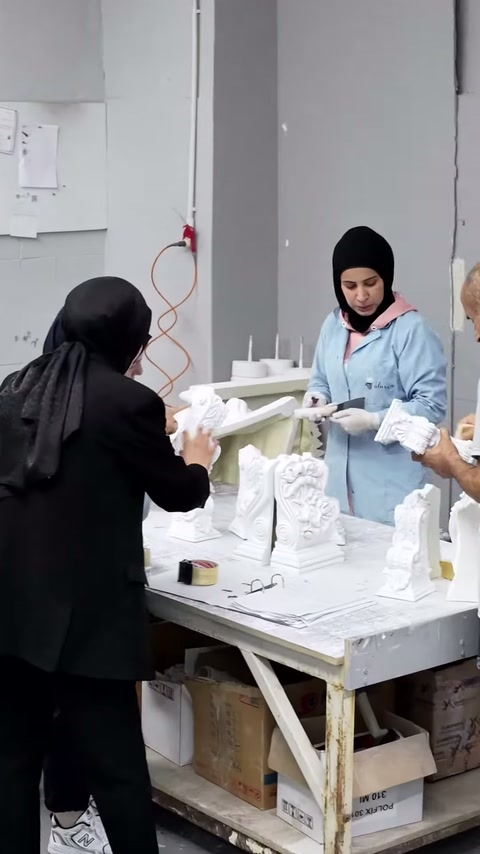 Eldivenli çalışan dekoratif elemanı kontrol ederken sunucu yanında bekliyor.