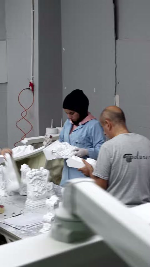 Tezgâh çevresindeki ekip farklı beyaz aksesuarların yüzeylerini birlikte inceliyor.