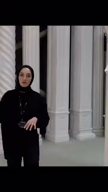 Sunucu, yüksek yivli sütunların önünde dekoratif uygulamayı açıklıyor.