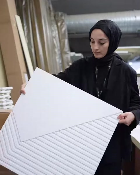 Görevli, çizgili yüzeye sahip dekoratif paneli yakından gösteriyor