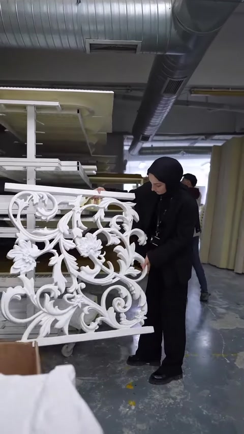 Kıvrımlı bitkisel motiflere sahip beyaz dekoratif panel sergileniyor