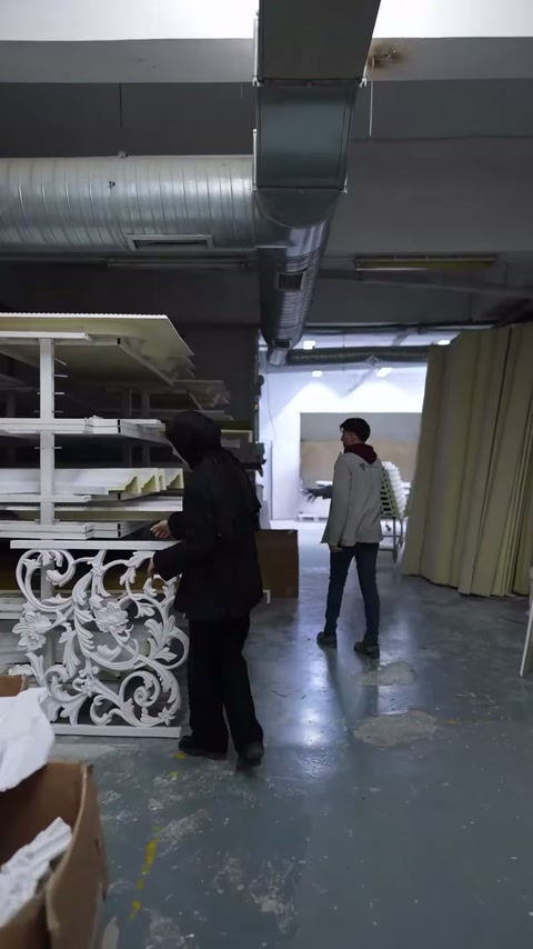 Beyaz kıvrımlı panel, üretim tezgâhları ve çalışanlarla birlikte görülüyor.