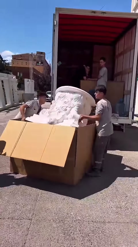 Kıvrımlı süslemeli büyük parça iki çalışan tarafından dengeleniyor