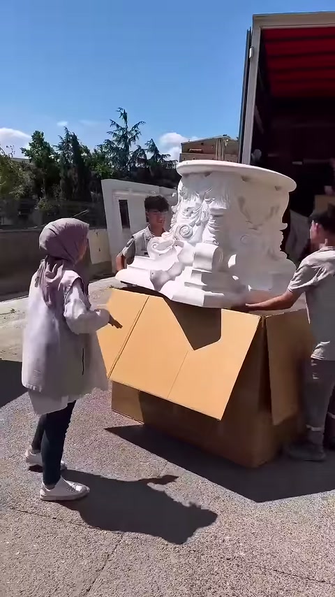 İki çalışan ürünü yan kenarlarından kavrayarak dengede tutuyor