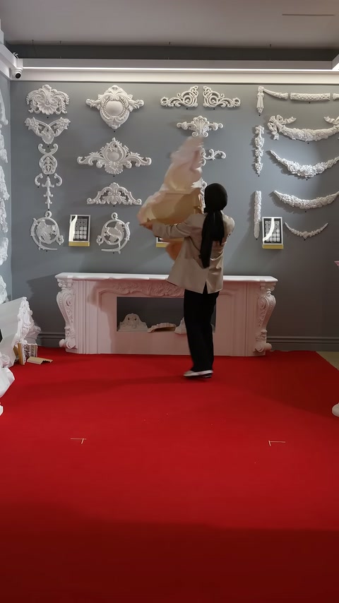 Büyük beyaz süsleme parçası showroomda havaya kaldırılmış halde görülüyor.