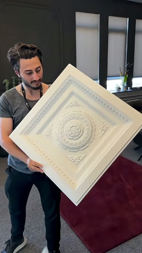 Kare panelin katmanlı kenarları avizeli salon içerisinde yakından seçiliyor.