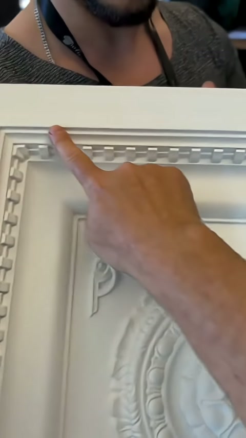 Sunucu parmağıyla panelin üst bölümündeki tekrarlı bordürü işaretliyor.