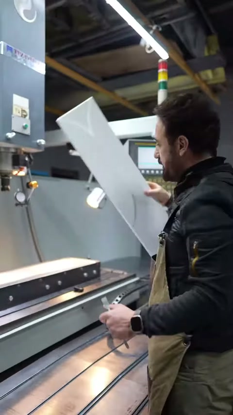 Operatör uzun beyaz paneli dik konuma getirerek tezgâhtan çıkarıyor