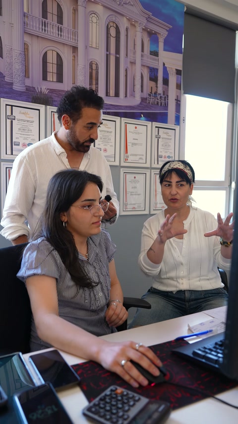 Bilgisayar başındaki ekip, tasarımcının dekorasyon açıklamalarını dikkatle dinliyor.