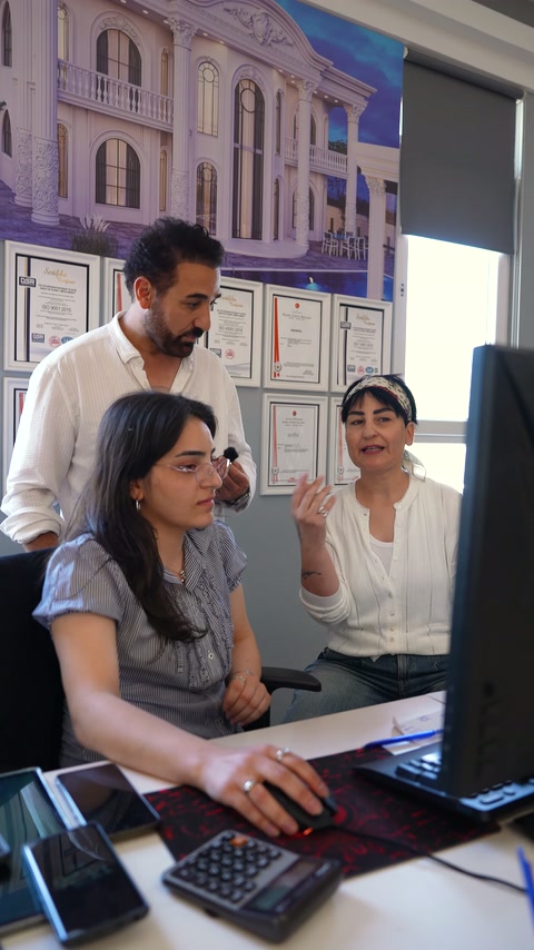 Selda Hanım masa üzerindeki bilgisayar yanında proje detaylarını açıklıyor.