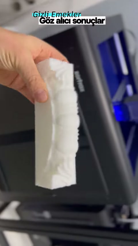 Beyaz üretim örneği, kabartmalı kenarı görünecek biçimde tutuluyor