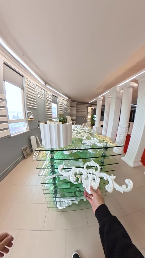 Cam sergi masası ve sütun sıralarını kapsayan showroom görünümü