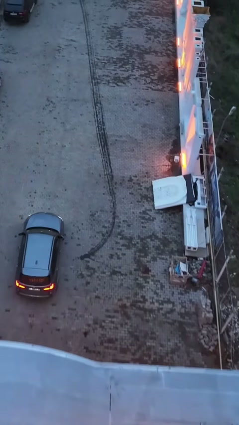 Avlu tarafındaki sütunlu duvar, araç geçişinin yanında sıcak ışıkla vurgulanıyor