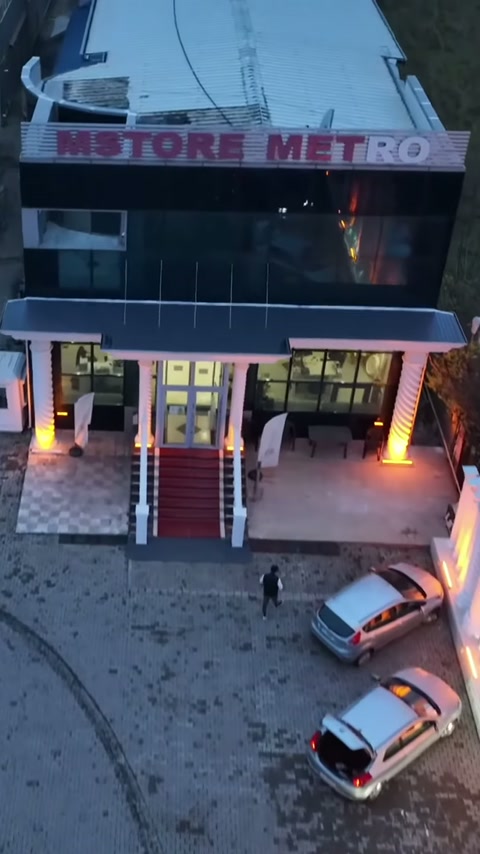 Kırmızı basamaklı bina girişi, aydınlatılmış dekoratif kolonlarla çevreleniyor
