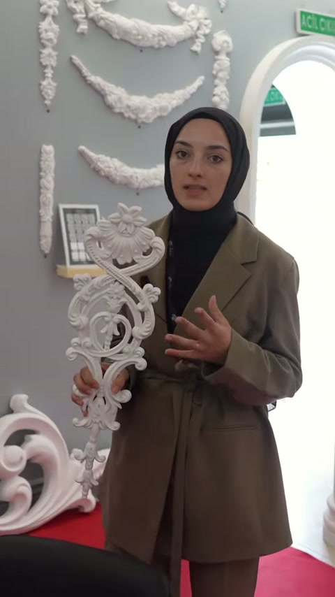 Sunucu uzun süsleme parçasının kıvrımlı detaylarını eliyle destekliyor