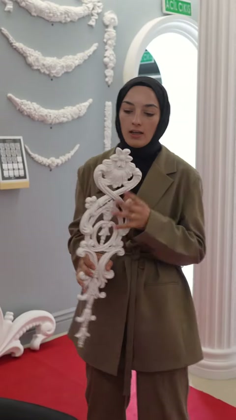Kabartmalı beyaz motif, sütunlu showroom içinde yakından gösteriliyor