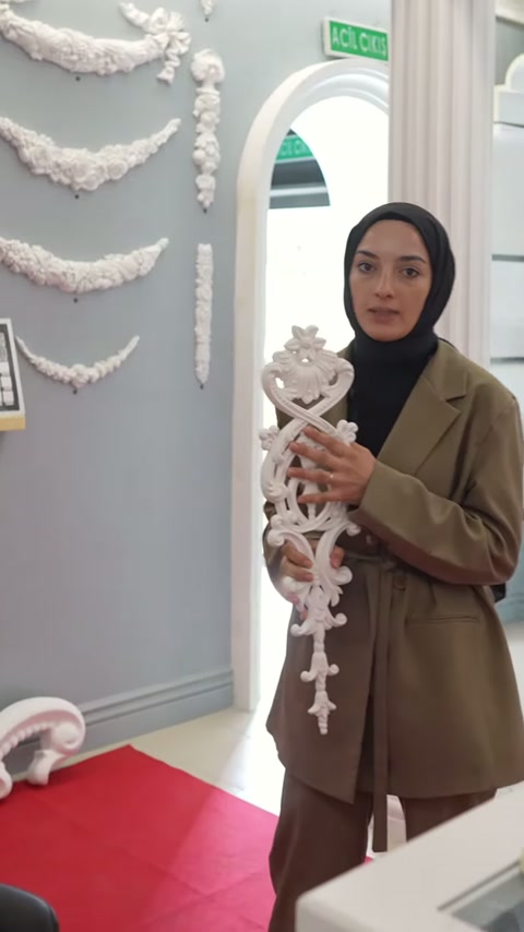Sunucu pembe sütunun yanında dekoratif parçayı önden gösteriyor
