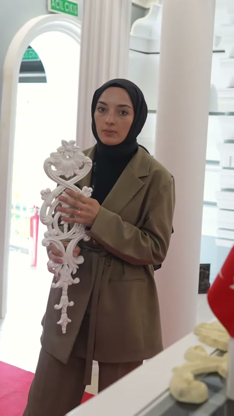 Dikey beyaz süsleme, sütunlar arasındaki teşhir bölümünde inceleniyor