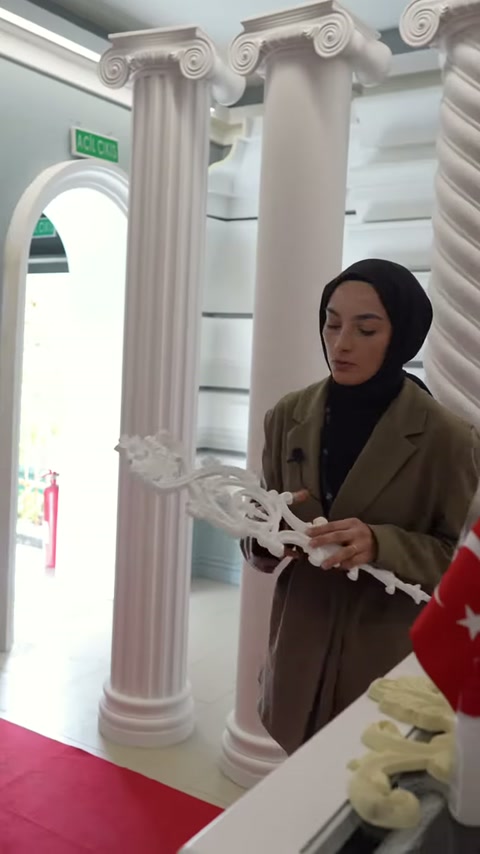 Uzun beyaz süsleme modeli yatay konumda iki elle tutuluyor
