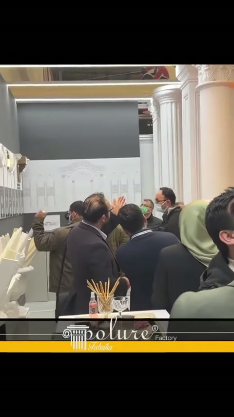 Beyaz sütunlar önünde katılımcılar teknik çizimli panoları gözden geçiriyor