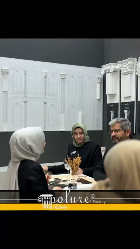 Görüşme masasında oturan ziyaretçiler, sütun çizimleri eşliğinde konuşuyor