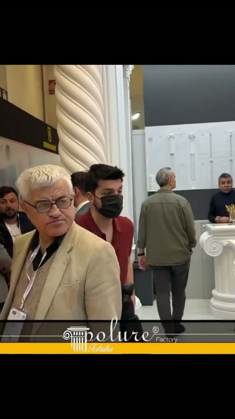 Burgulu sütun yanında katılımcılar stand içindeki sergiyi geziyor