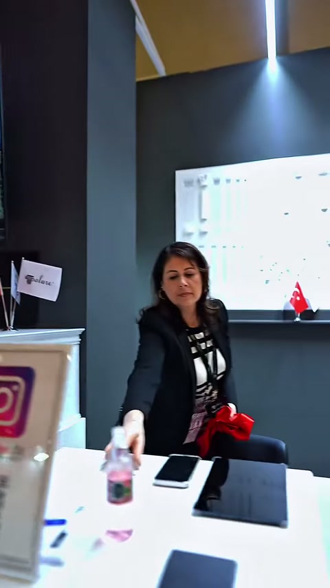 Fuar standının görüşme masasında görevli ve ürün panosu görülüyor