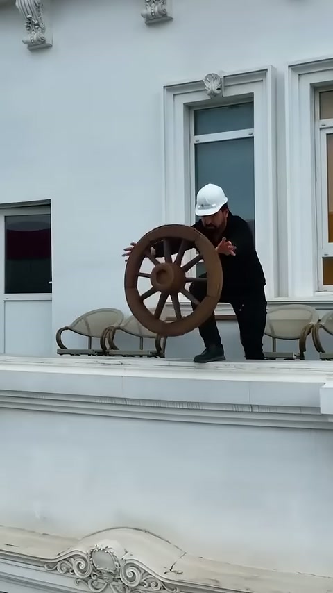 Usta terasta rustik tekerlek süsünü elleriyle gösteriyor.