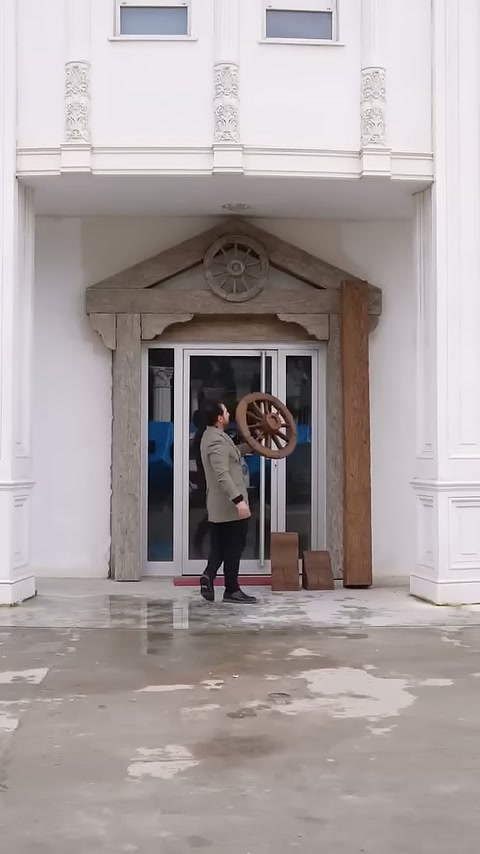 Kapı önündeki usta yuvarlak dekoratif parçayı yukarı kaldırıyor.