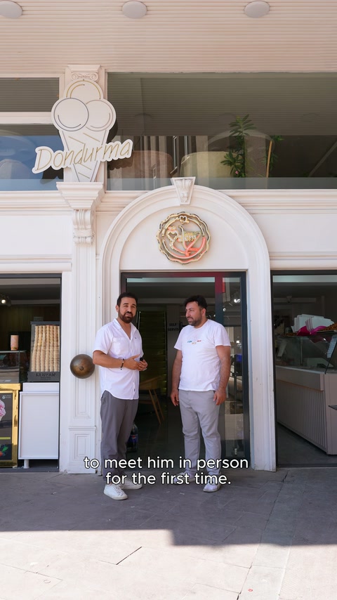 İki kişi, rozetli kemer düzenlemesi bulunan pastane kapısında duruyor.