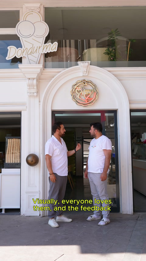 İki kişi, simetrik pilasterlerle çevrelenen kemerli kapının önünde görüşüyor.