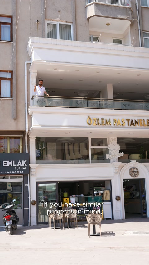 Apartman altındaki pastanenin geniş cephesi, balkonları ve giriş süslemeleri görülüyor.